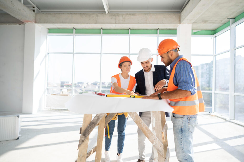 construction workers and a supervisor looking at a building plan