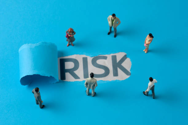 Business people figurines looking at the phrase "Risk"